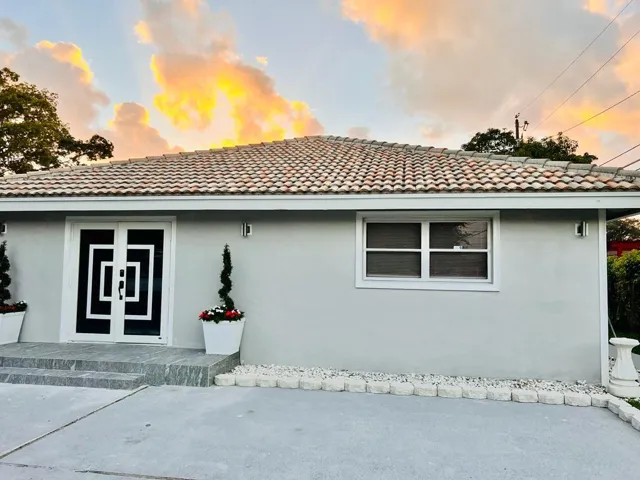 Modern single-story residence featuring a freshly resurfaced concrete driveway, geometric black and white entry door with contemporary styling, and a new tile roof with clean geometric patterning