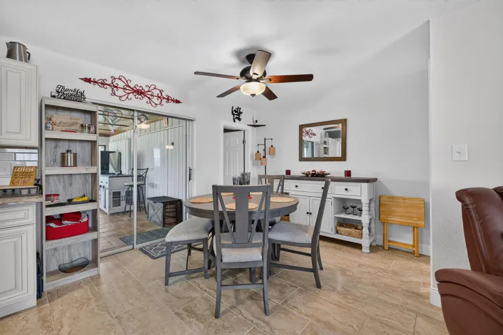 Spacious dining area featuring neutral tile flooring, a ceiling fan with integrated lighting, and white walls