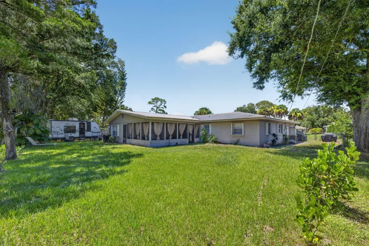 Expansive backyard featuring a large screened-in patio, mature trees, and a spacious lawn