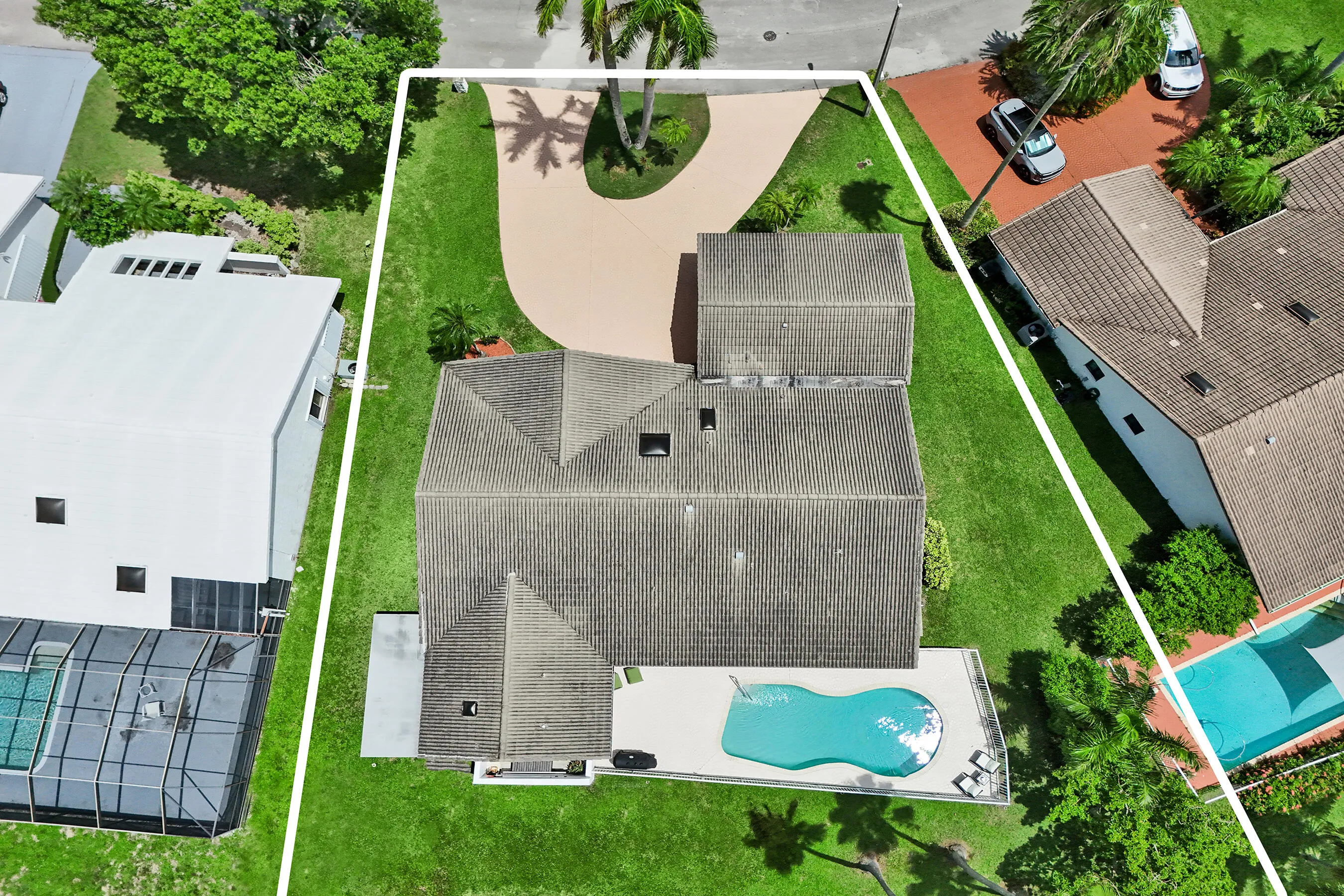 Architectural roof, organic-shaped pool, paved pool deck, large green space, and a paved driveway