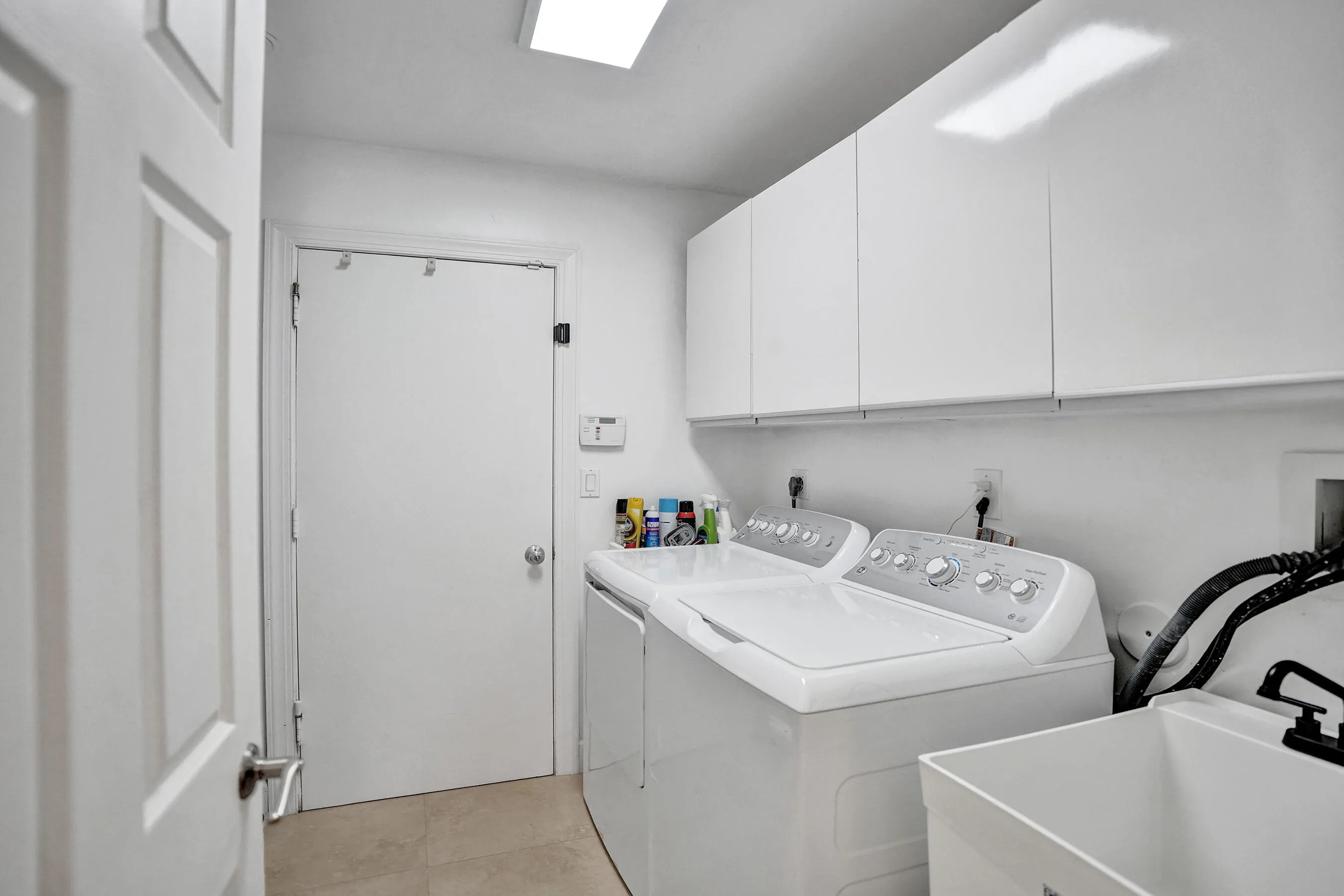 Utility room with high-gloss white cabinetry, a rectangular ceiling light fixture, and a built-in utility sink