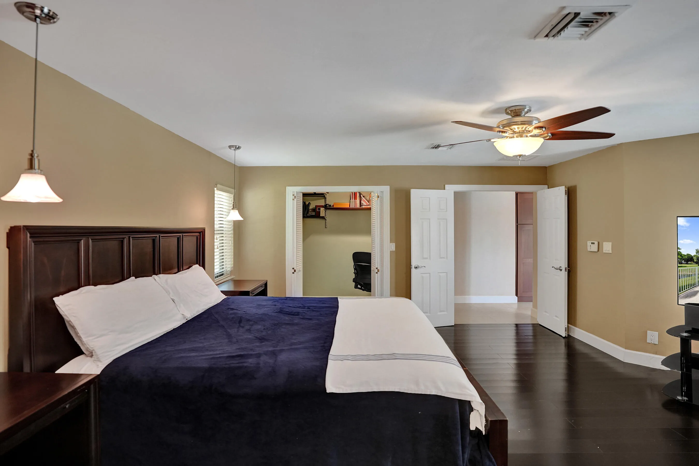 Wood-finish flooring, two pendant light fixtures, and a ceiling fan with integrated lighting