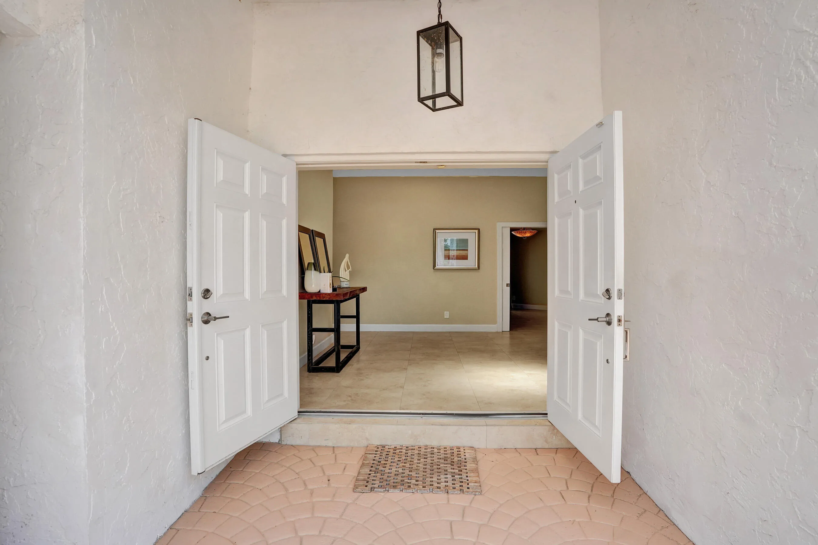 Double entry doors opening to an interior with neutral wall colors and tile flooring