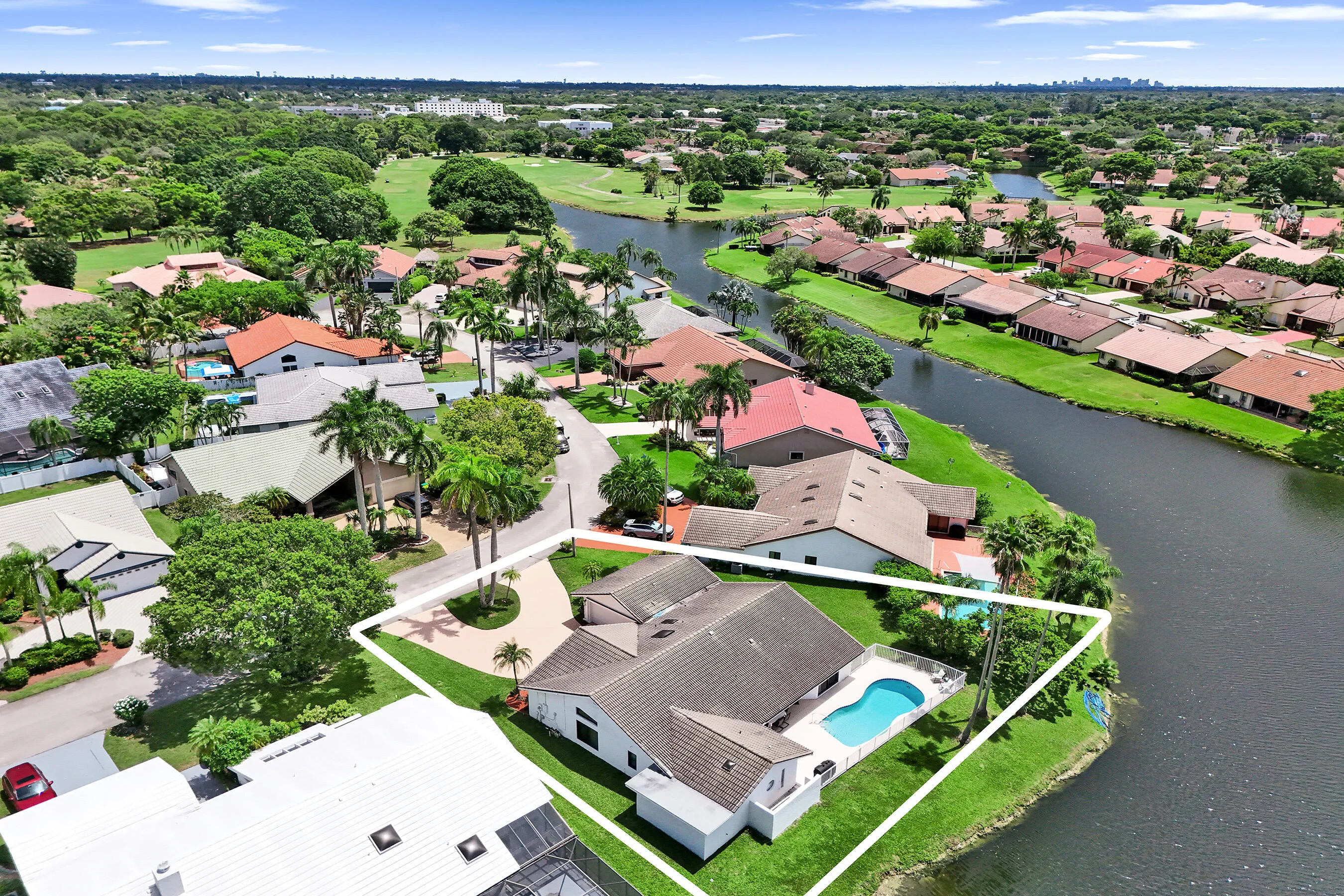 Waterfront property featuring a private swimming pool, mature palm trees, and a paved driveway