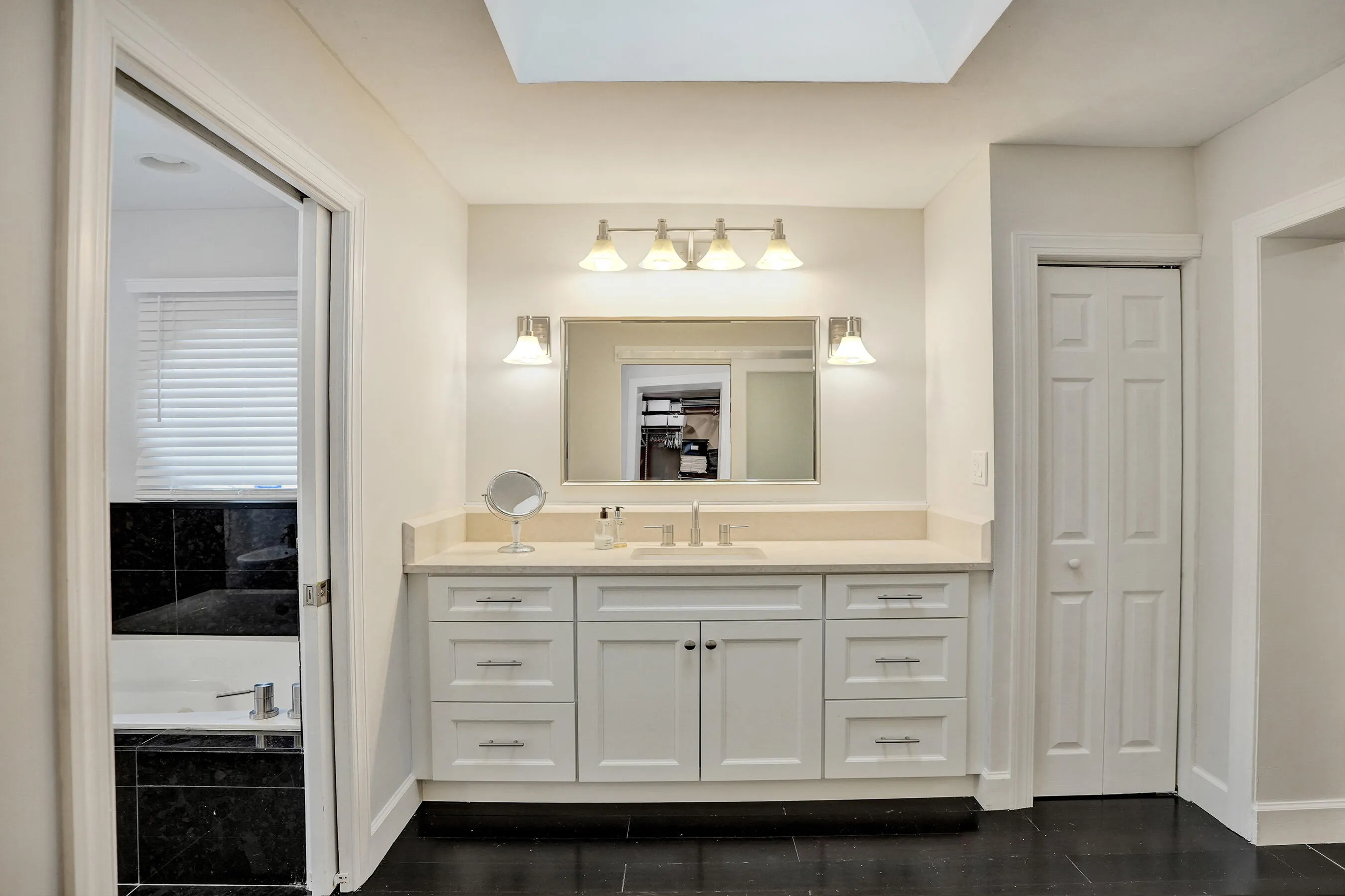 Vanity with a light-toned countertop, white cabinetry, undermount sink, and brushed nickel fixtures