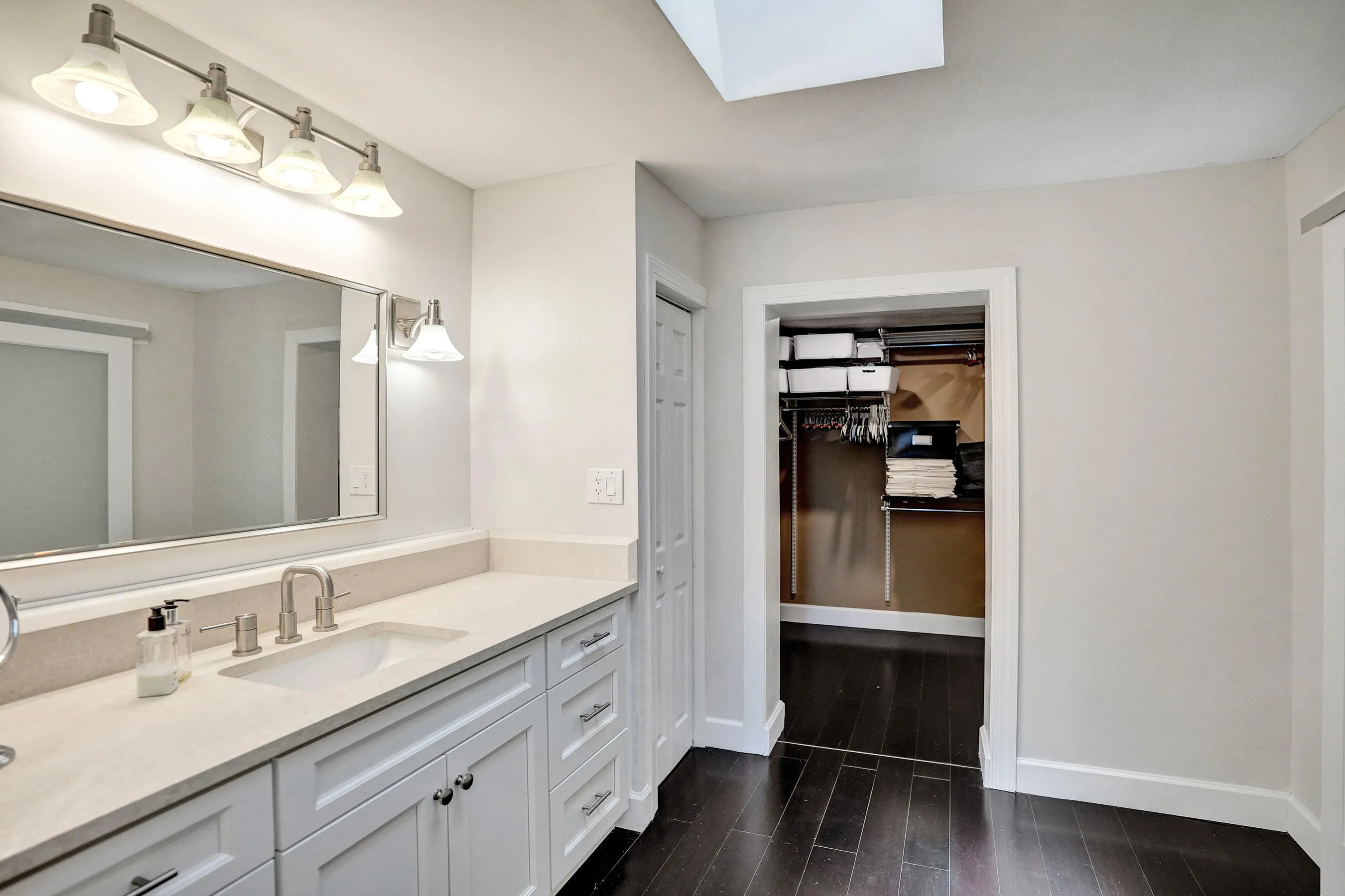 Vanity with an undermount sink, brushed nickel faucet, large mirror, and white cabinetry