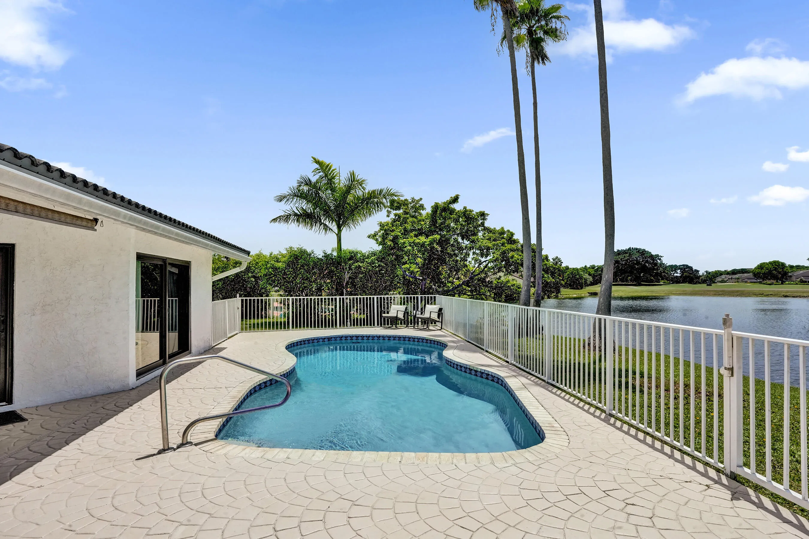Freeform pool with integrated steps, surrounded by a patterned concrete patio
