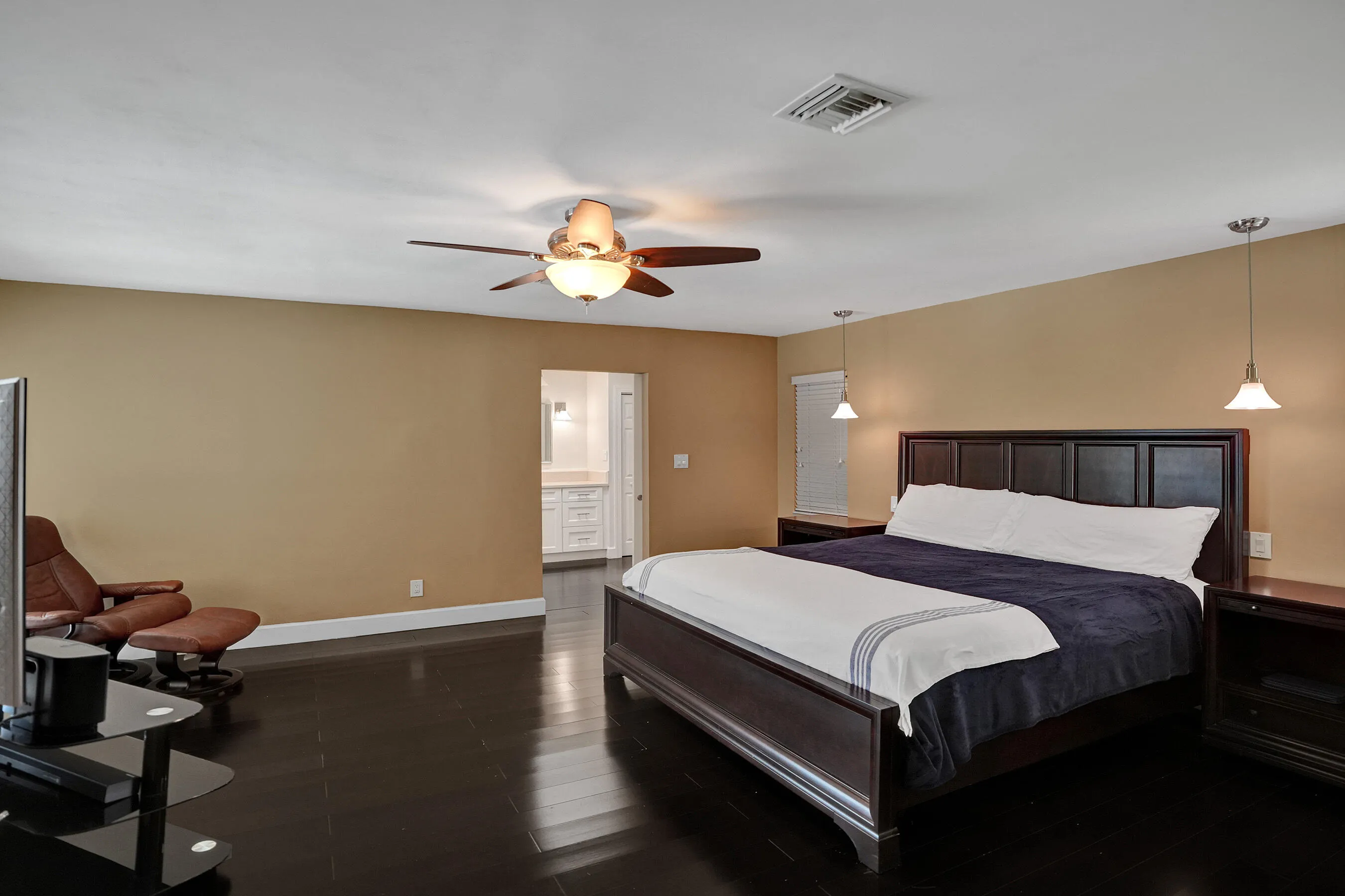 Spacious room with dark wood-finish flooring, a ceiling fan with integrated lighting, and dual pendant lights