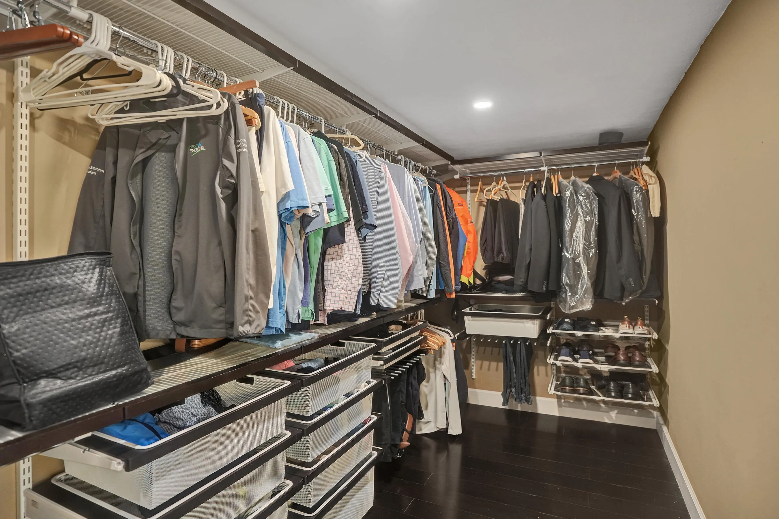Custom closet system featuring dark wood-finish flooring, recessed lighting, and wall-mounted shelving