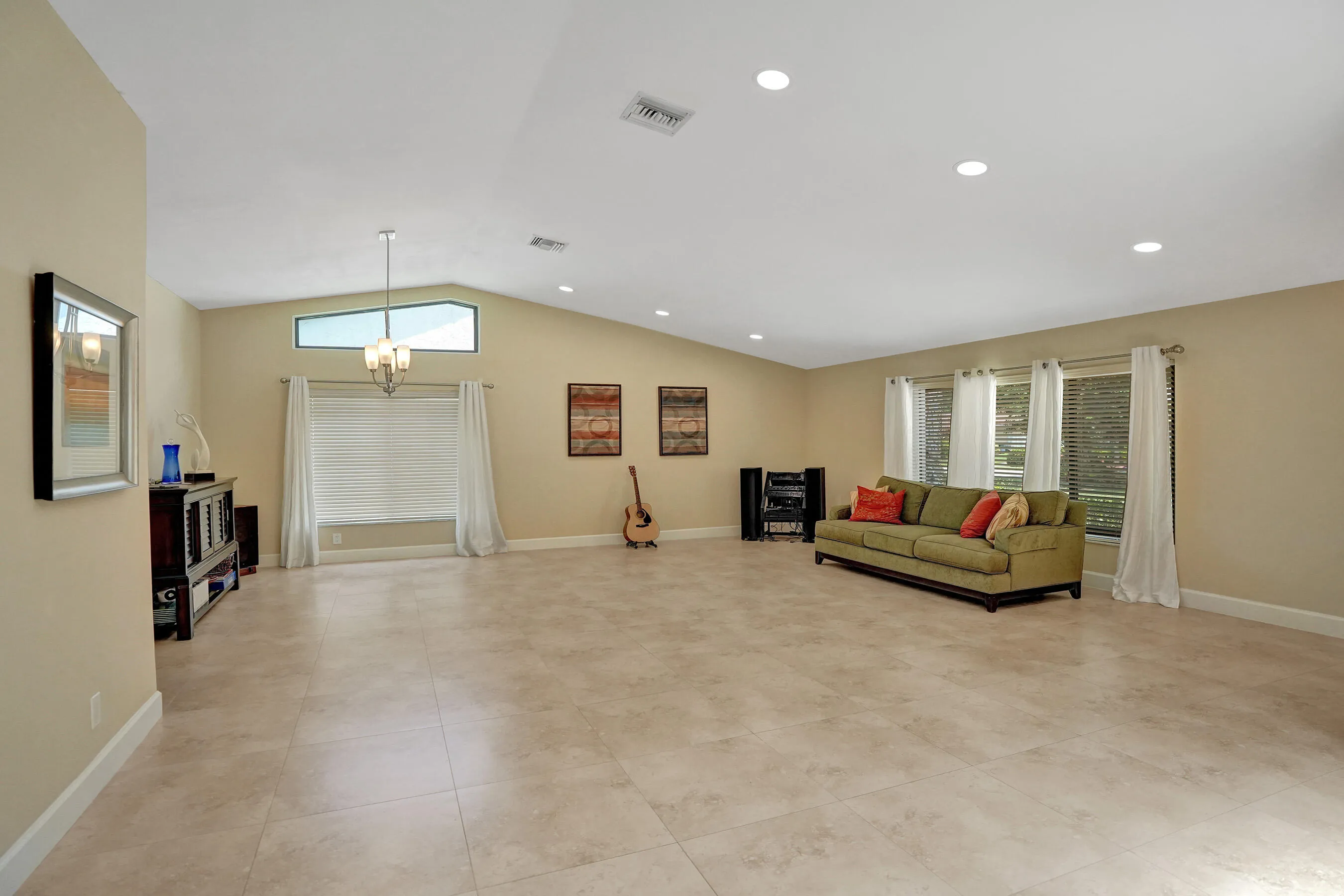 Vaulted ceiling, recessed lighting, tile flooring, transom window, and a prominent chandelier fixture
