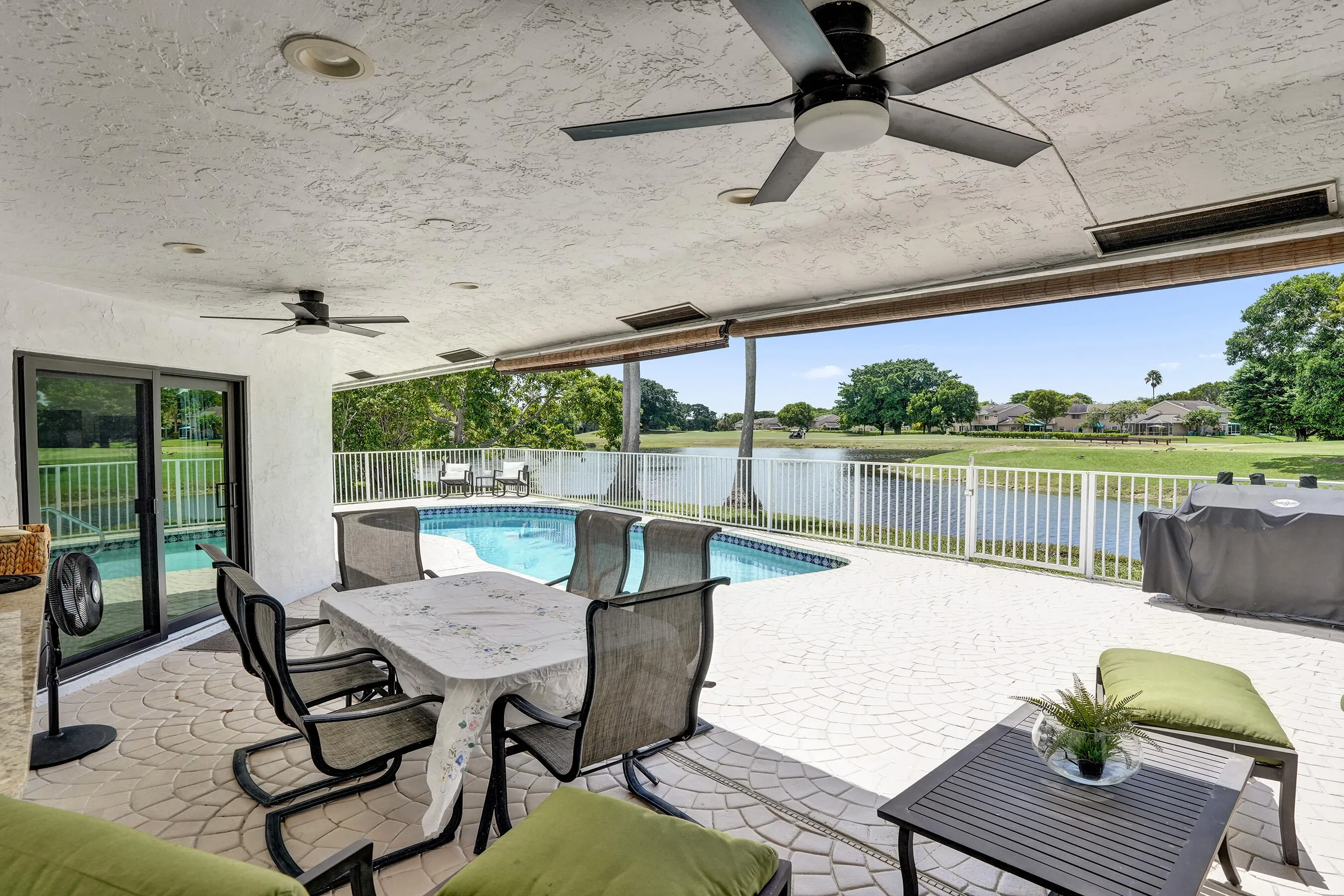 Covered patio with textured ceiling, ceiling fans, and patterned paver flooring
