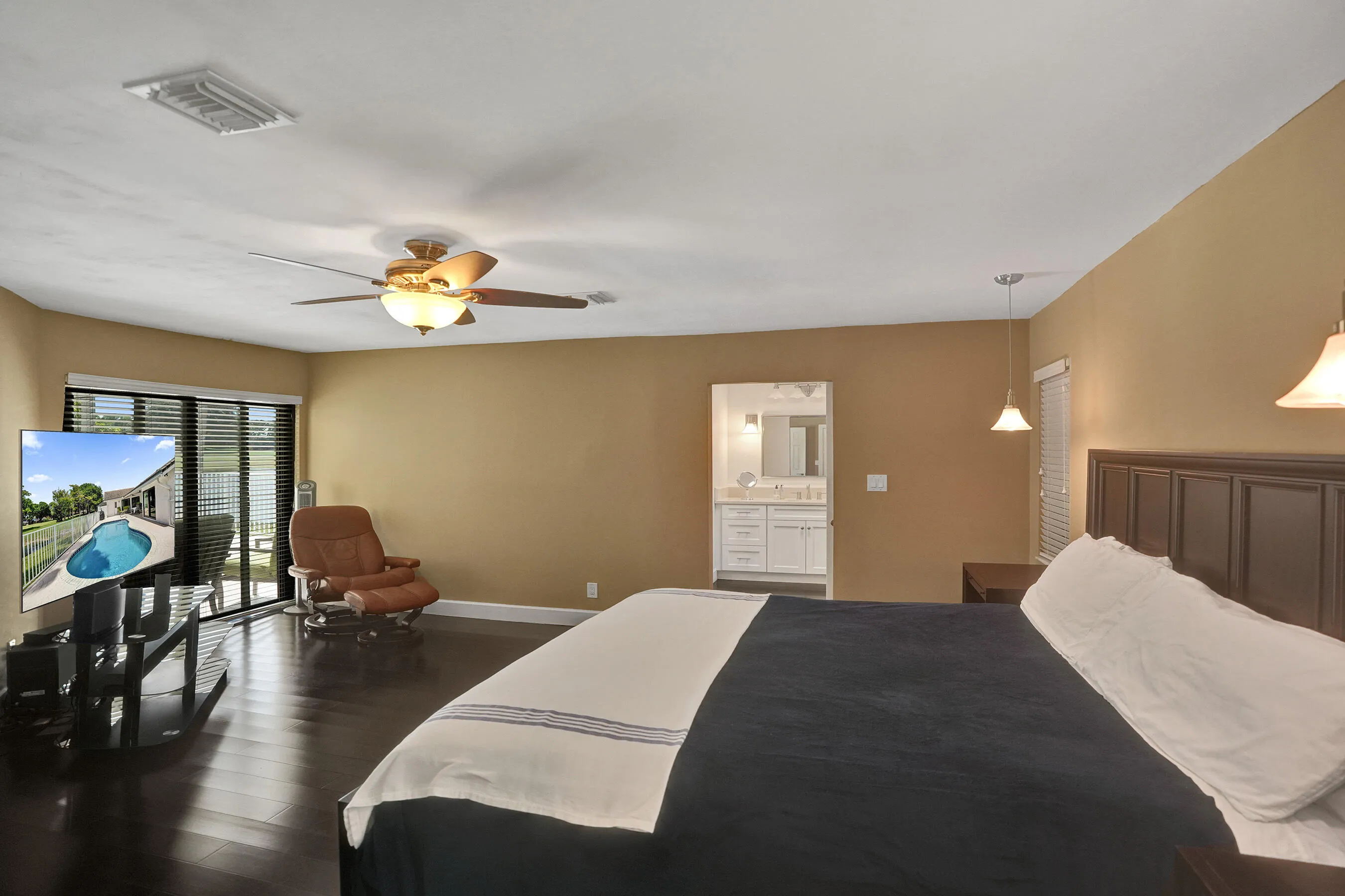 Rich wood-finish flooring, ceiling fan with integrated lighting, sliding glass door, and a built-in vanity with a mirror and lighting