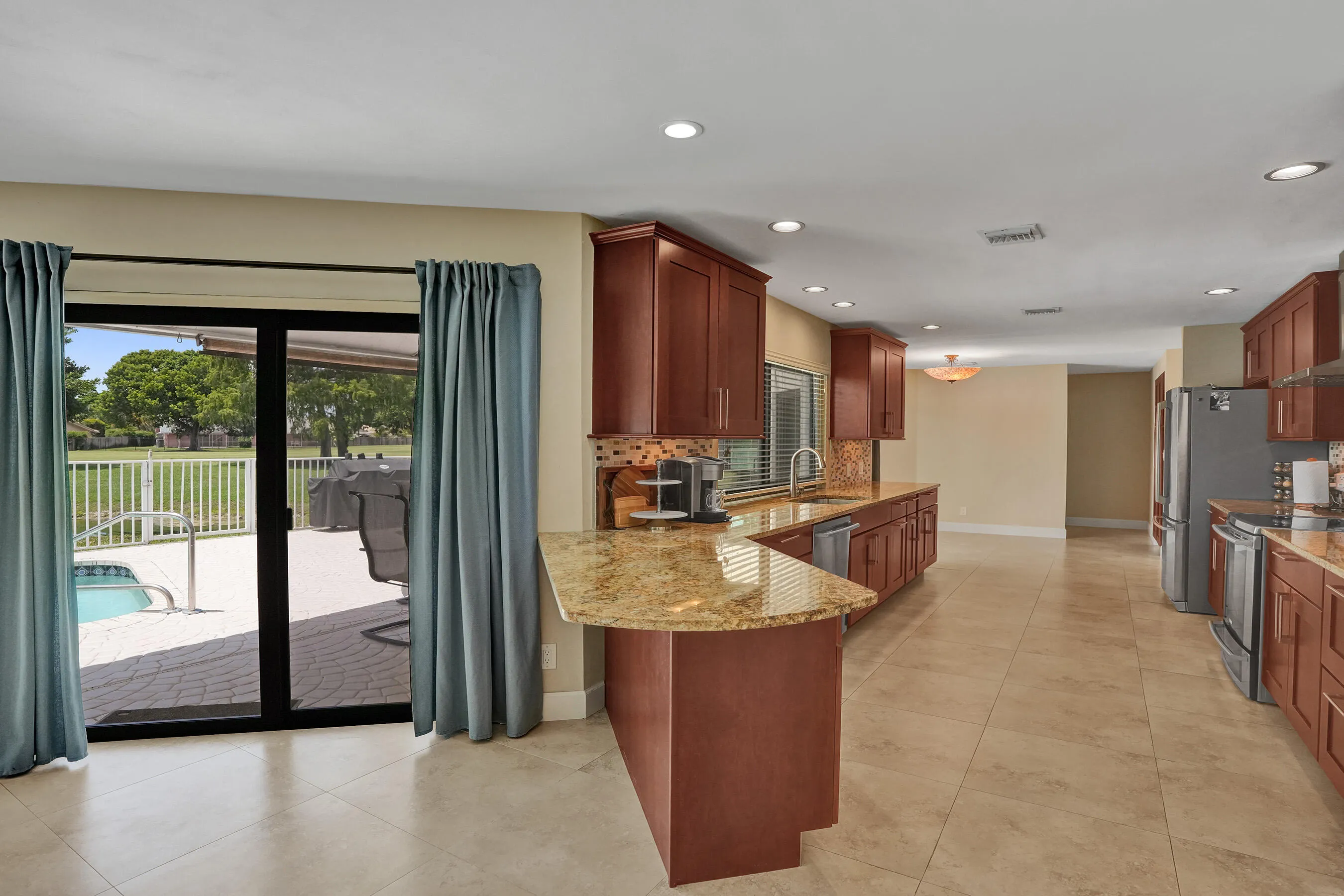 Open-concept kitchen featuring wood cabinetry, integrated stainless steel appliances, and a curved peninsula