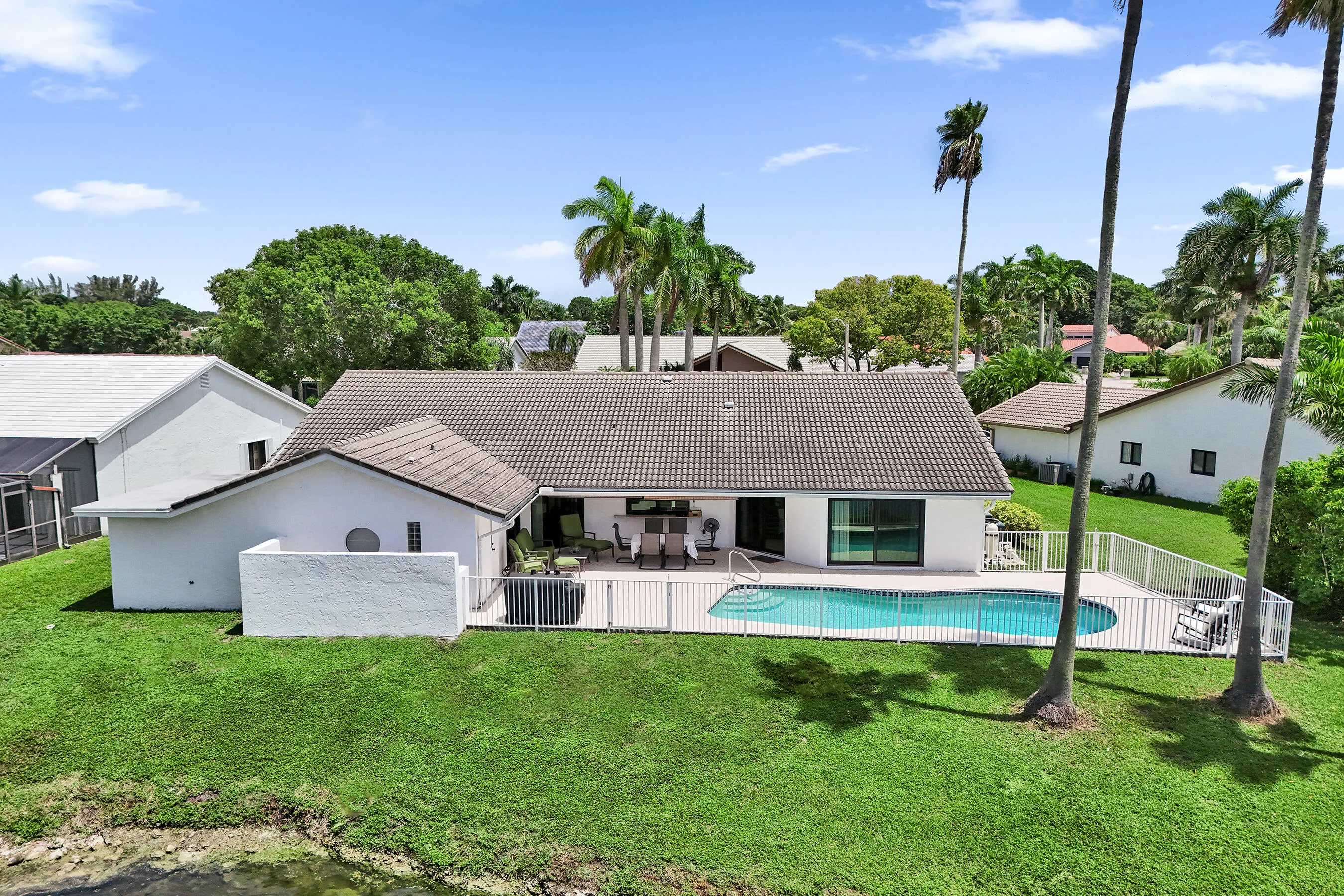 Exterior featuring a tile roof, a swimming pool, a fenced pool deck, and a manicured lawn