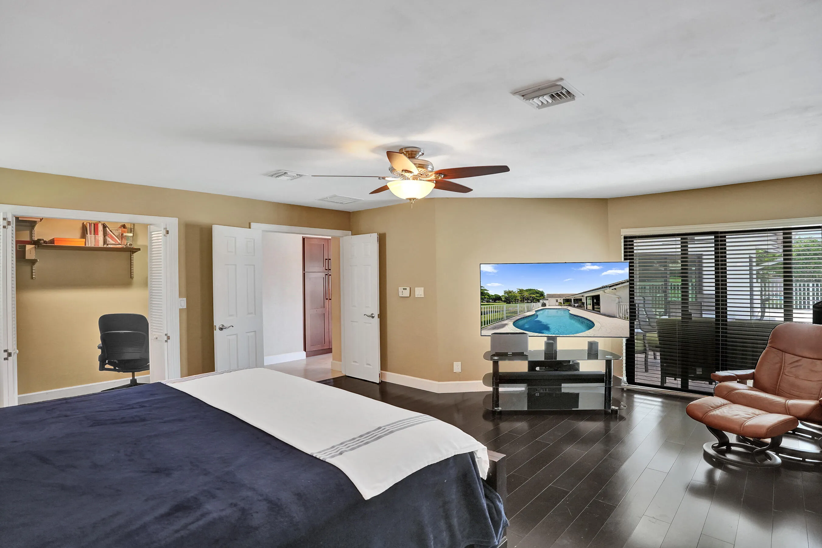Dark wood-finish flooring, ceiling fan, sliding glass doors, and built-in shelving