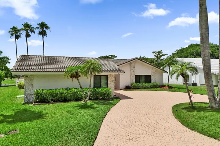 Single-story residence featuring a tile roof, light-colored exterior, and a patterned paver driveway