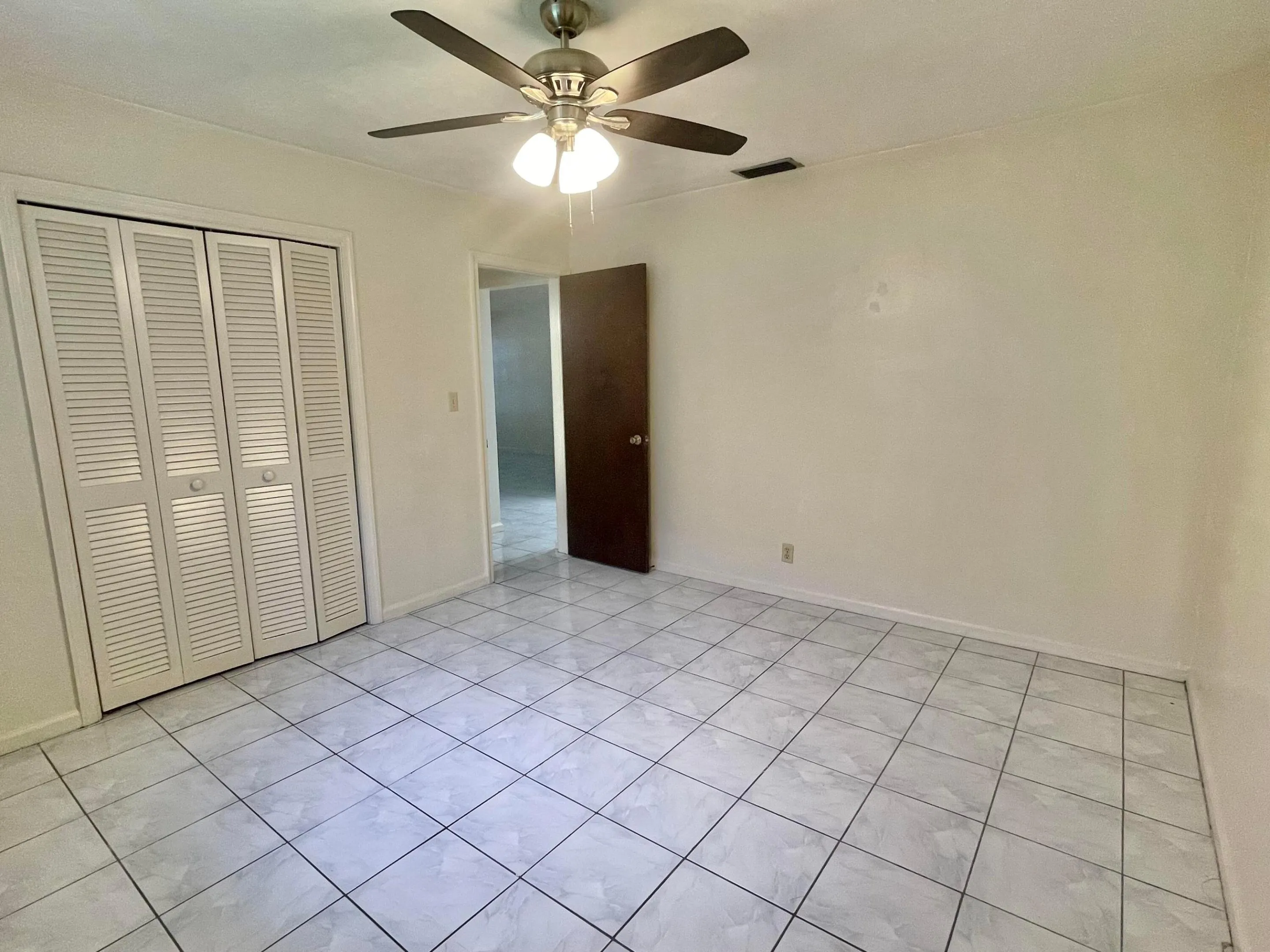 tile flooring, ceiling fan with integrated lighting, louvered bi-fold closet doors, and light-toned walls