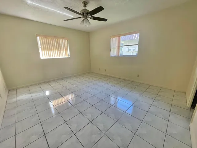 Tiled flooring throughout, two windows with vertical blinds, and a ceiling fan with integrated lighting