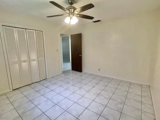 tile flooring, ceiling fan with integrated lighting, louvered bi-fold closet doors, and light-toned walls