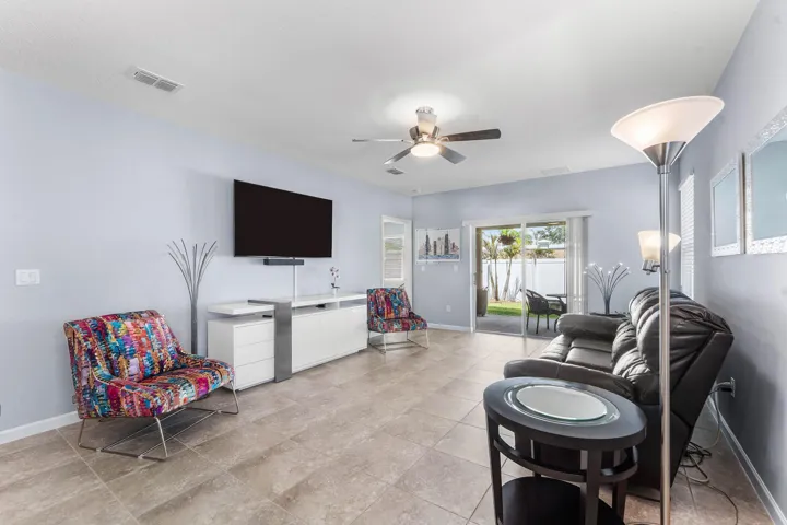 Spacious living area featuring tile flooring, ceiling fan, and sliding glass doors opening to an outdoor patio