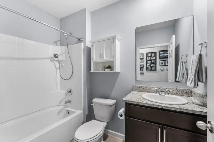 Vanity with speckled countertop, undermount sink, and dark wood-finish cabinetry
