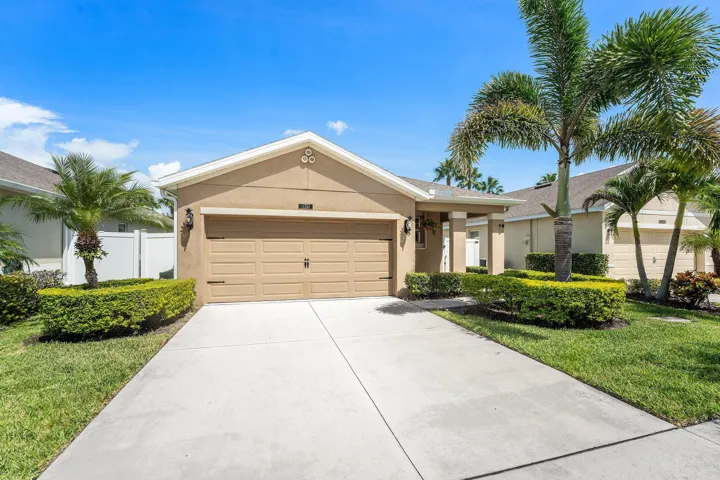 Single-story residence featuring a tan stucco exterior, an attached two-car garage, and a concrete driveway
