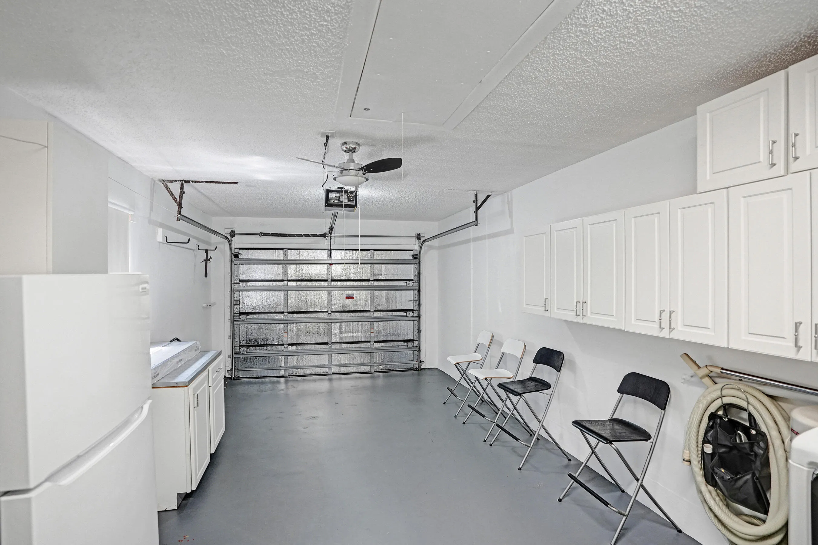 One car garage with cabniets, shleves and a fridge