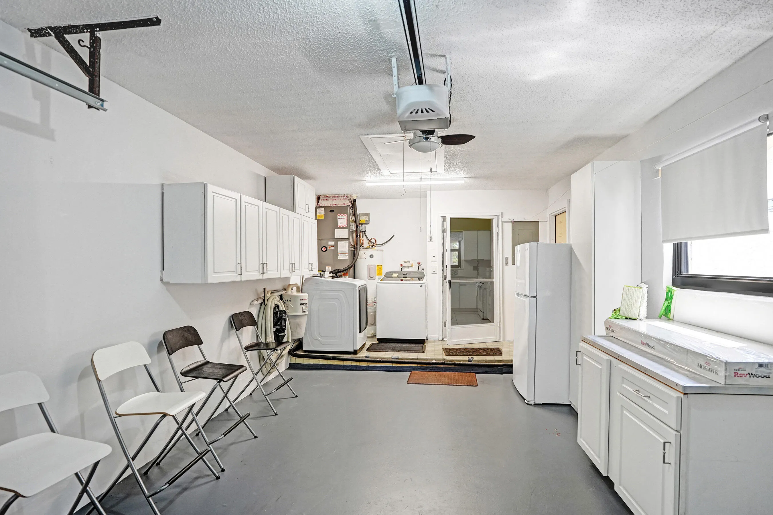 One car garage with cabniets, shleves and a fridge