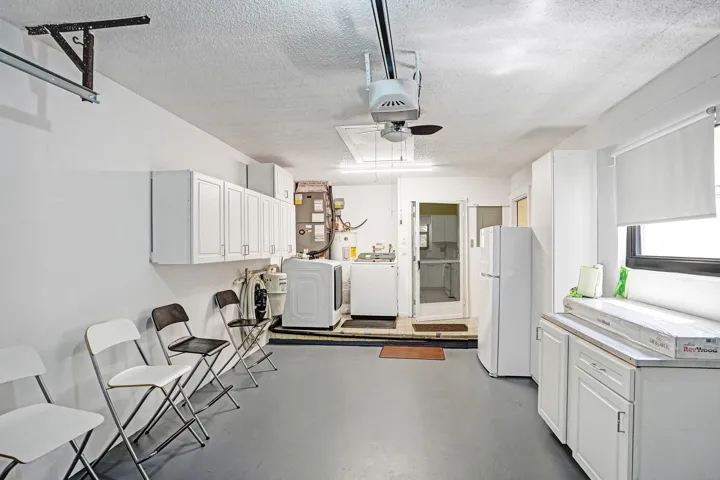 One car garage with cabniets, shleves and a fridge