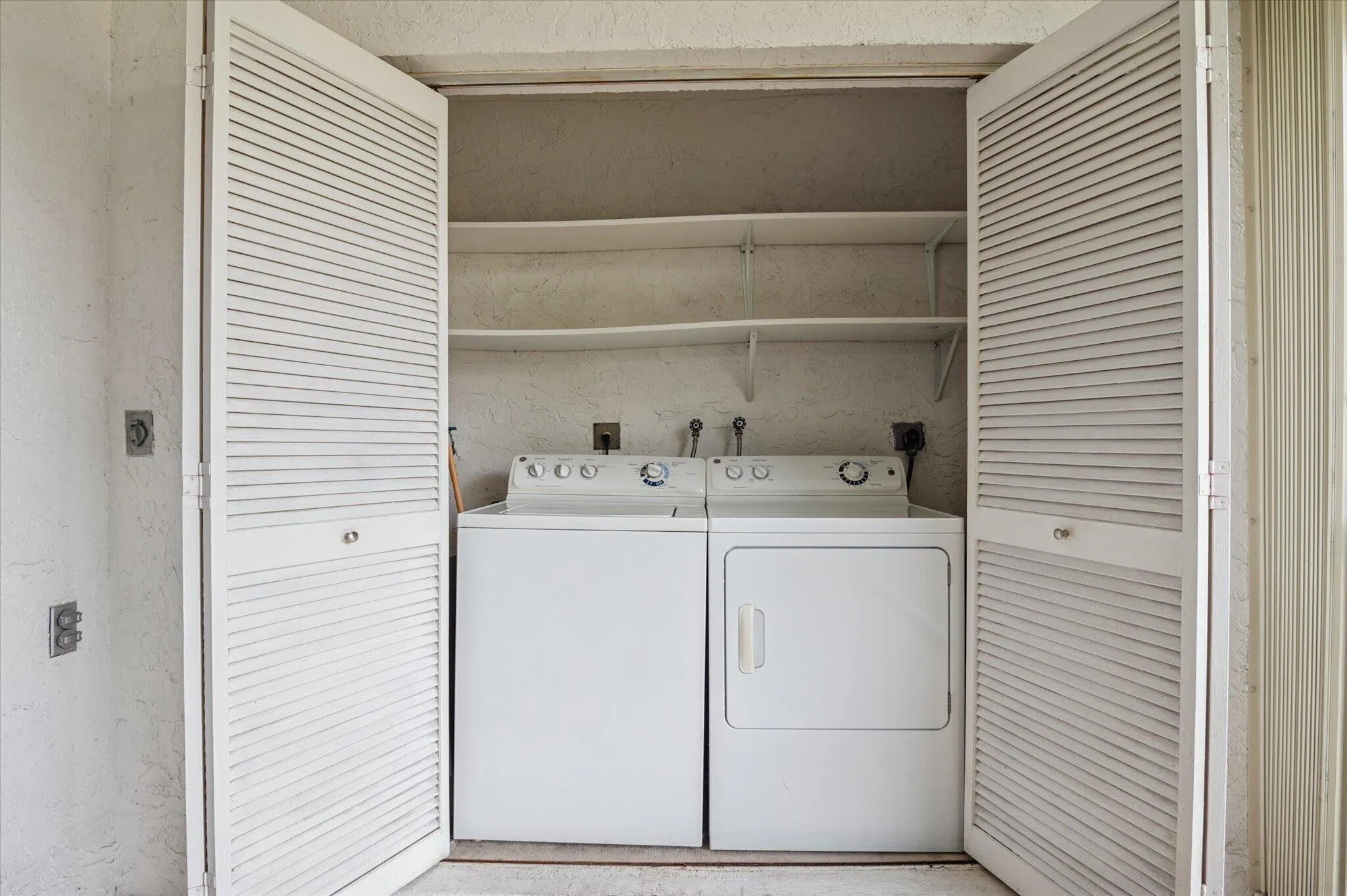 Laundry area with full-sized washer/dryer and storage