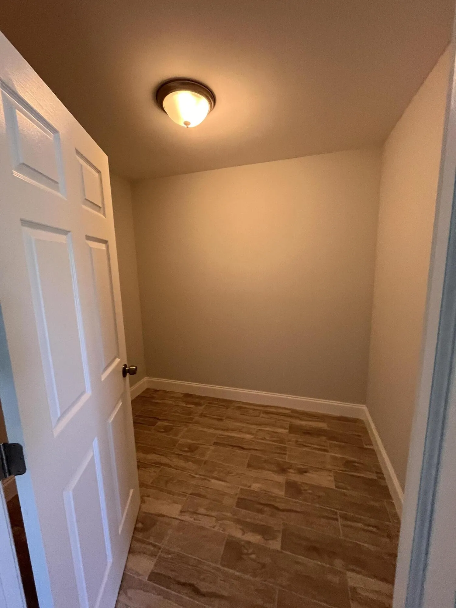 Recessed ceiling light fixture, wood-look tile flooring, and a paneled interior door