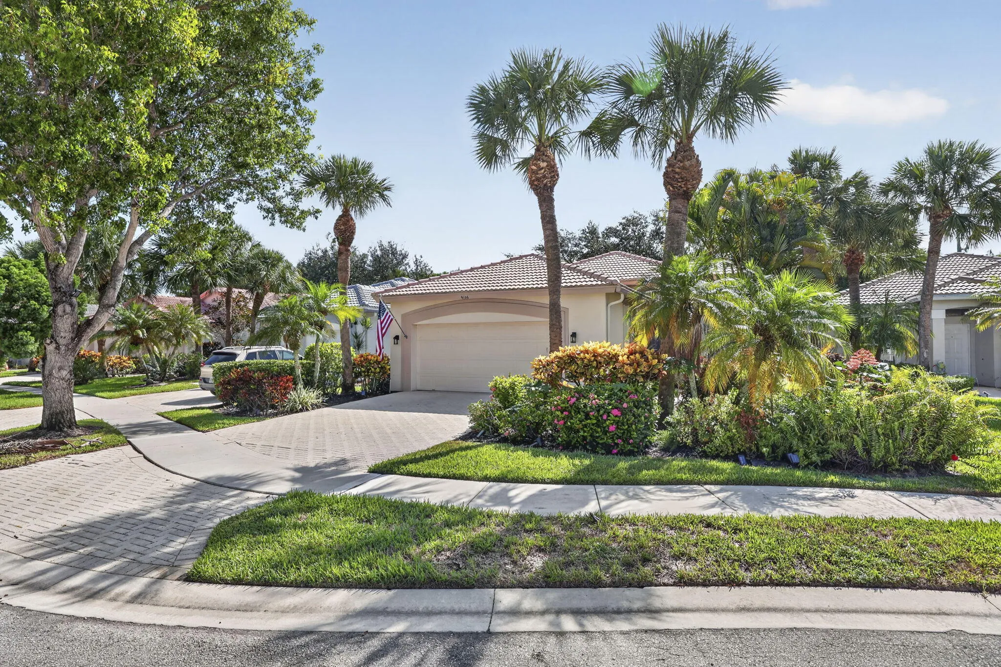 Mediterranean-style architecture with a tile roof, an arched garage door, and a paver driveway