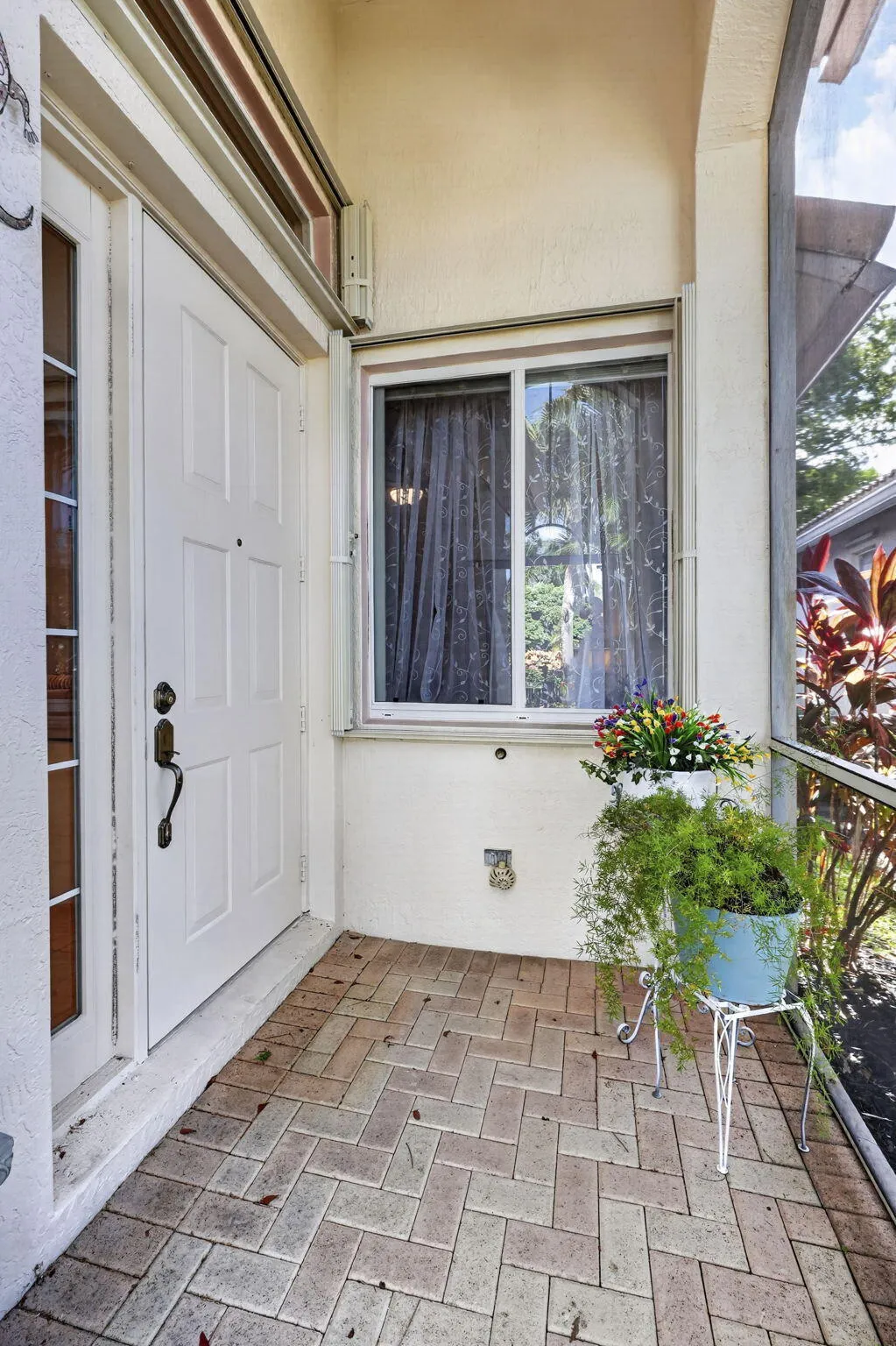 Entryway featuring a white paneled door, brick paver flooring, and a sliding window