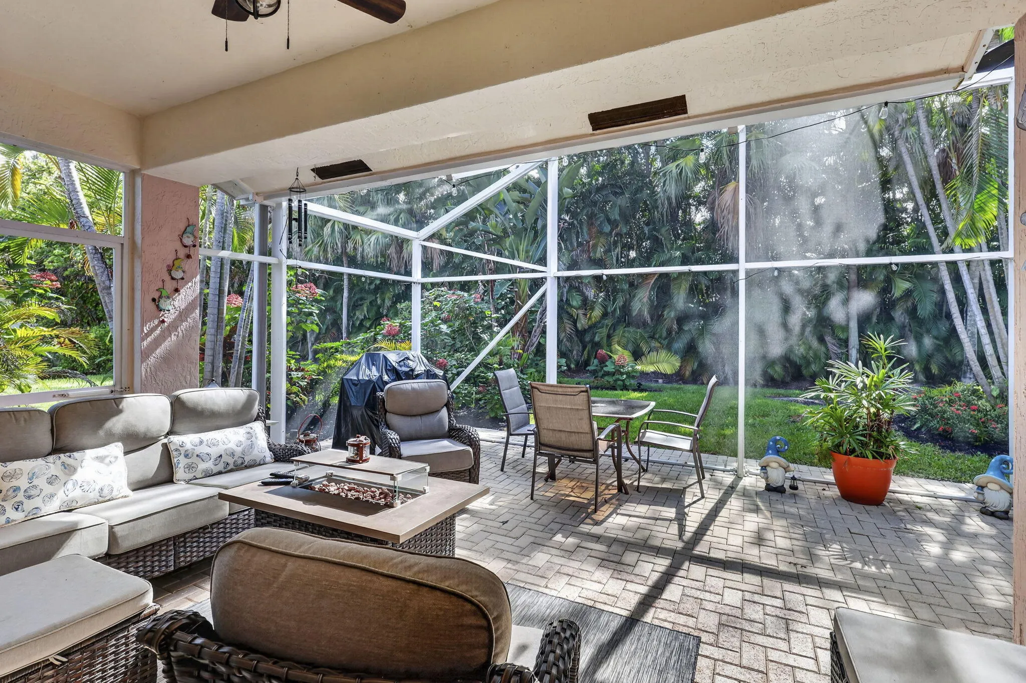 Screened lanai featuring paver flooring, a ceiling fan, and a lush green lawn