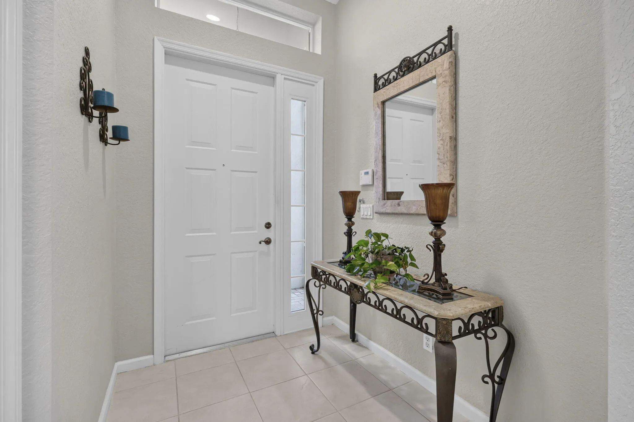 White paneled entry door with sidelight and transom window, set on tile flooring