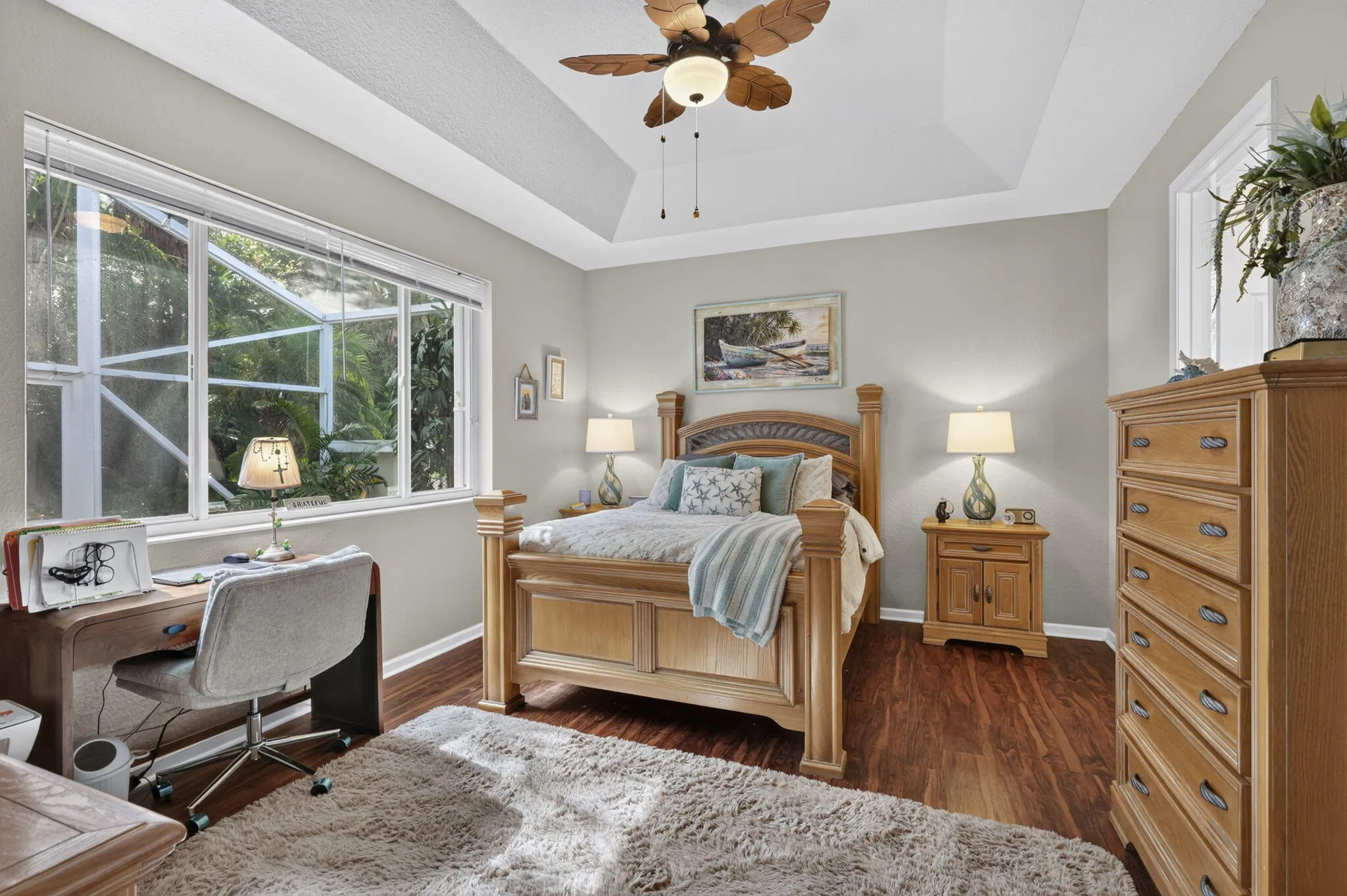 Recessed tray ceiling, wood-finish flooring, and a window with a garden outlook