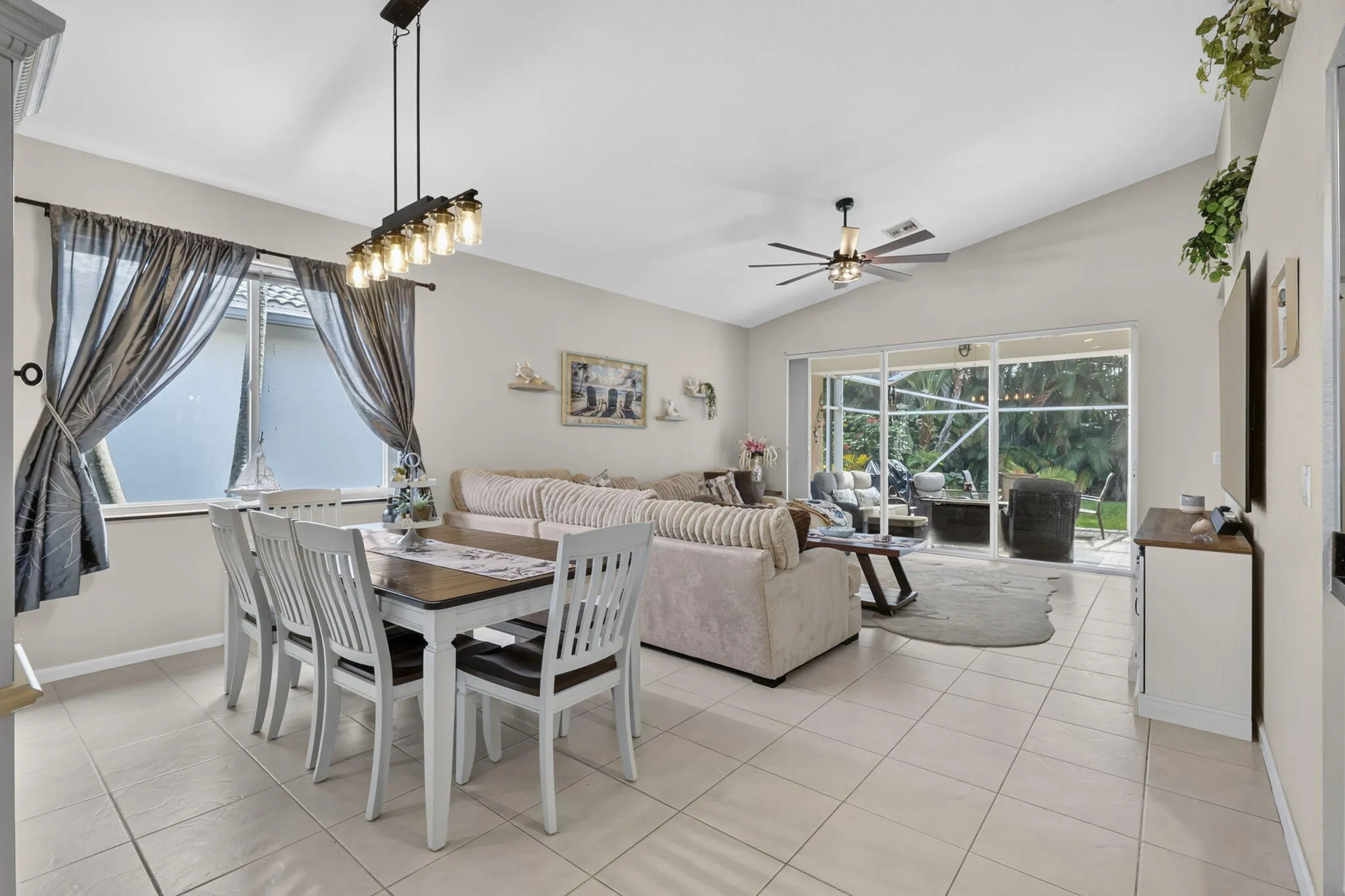 Vaulted ceiling, ceiling fan, sliding glass doors, and tile flooring