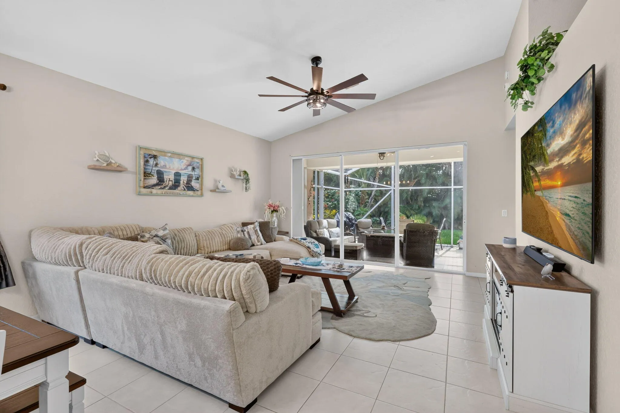 Vaulted ceilings, a dark wood-finish ceiling fan, and light-toned tile flooring