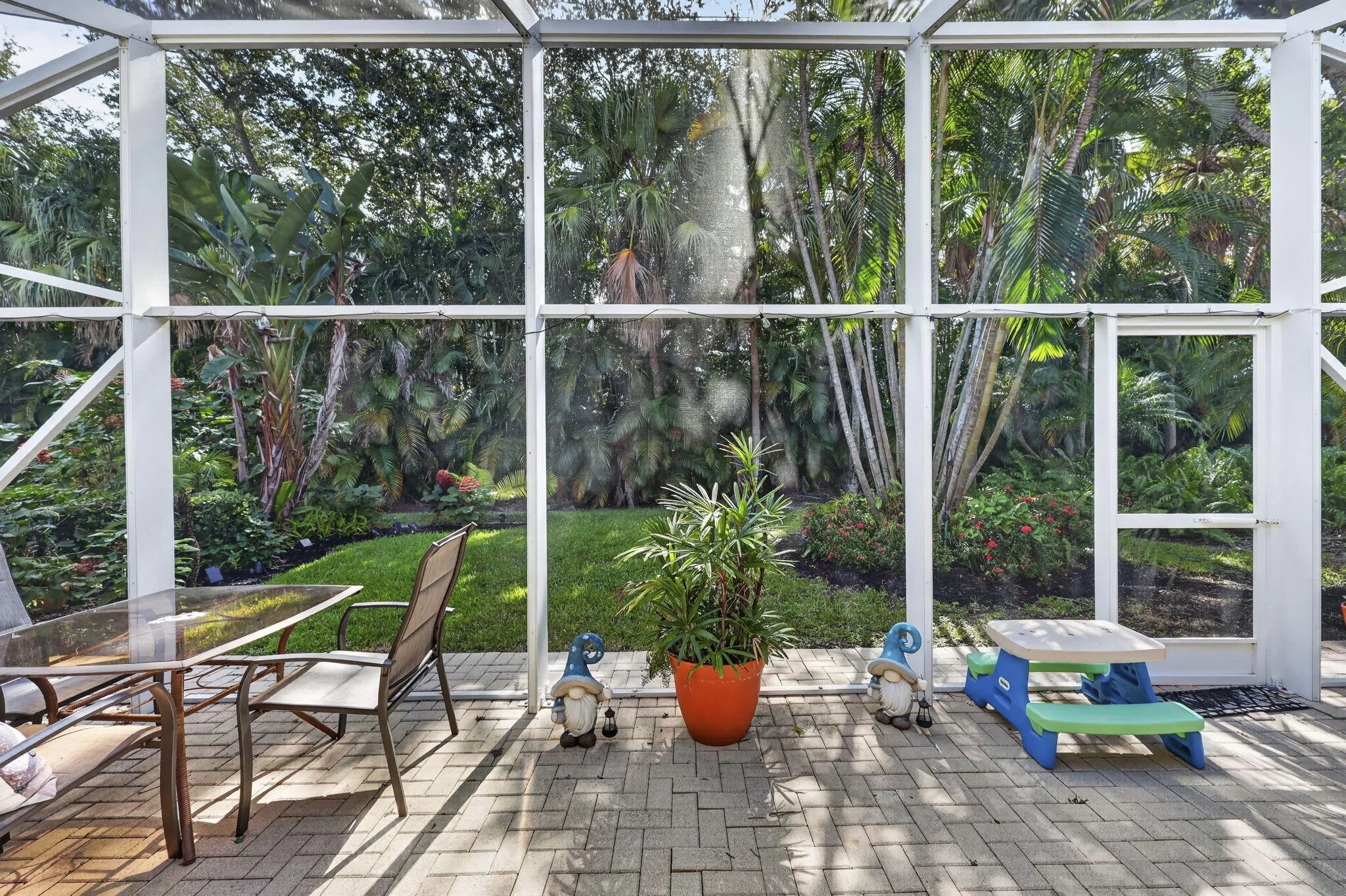 Screened lanai featuring paver flooring and lush perimeter landscaping