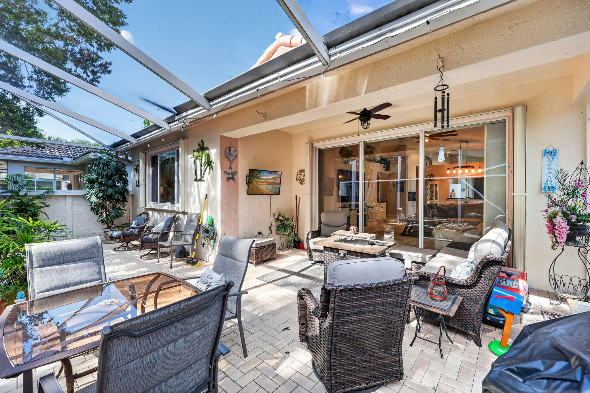 Expansive patio featuring a screened enclosure, paver flooring, multiple ceiling fans, and sliding glass doors