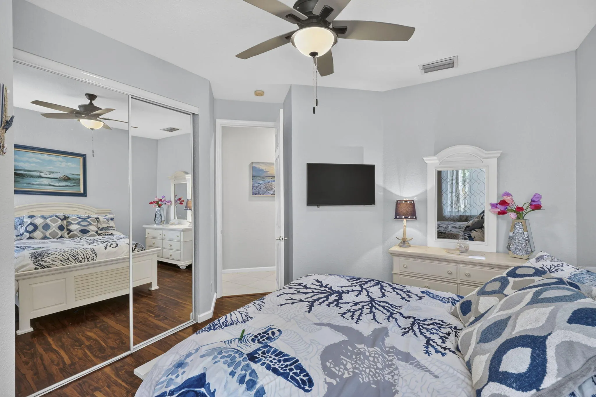 Mirrored closet doors, wood-finish flooring, and a ceiling fan with integrated lighting