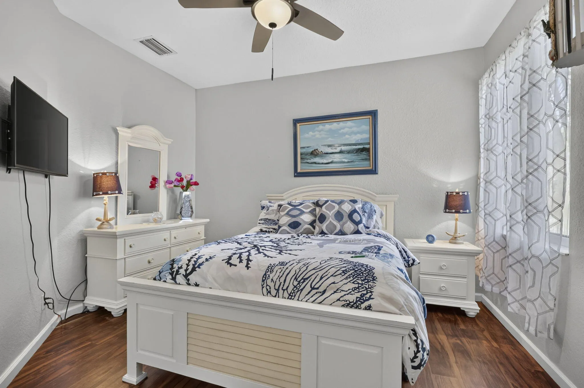 Wood-finish flooring, ceiling fan, and window with curtains