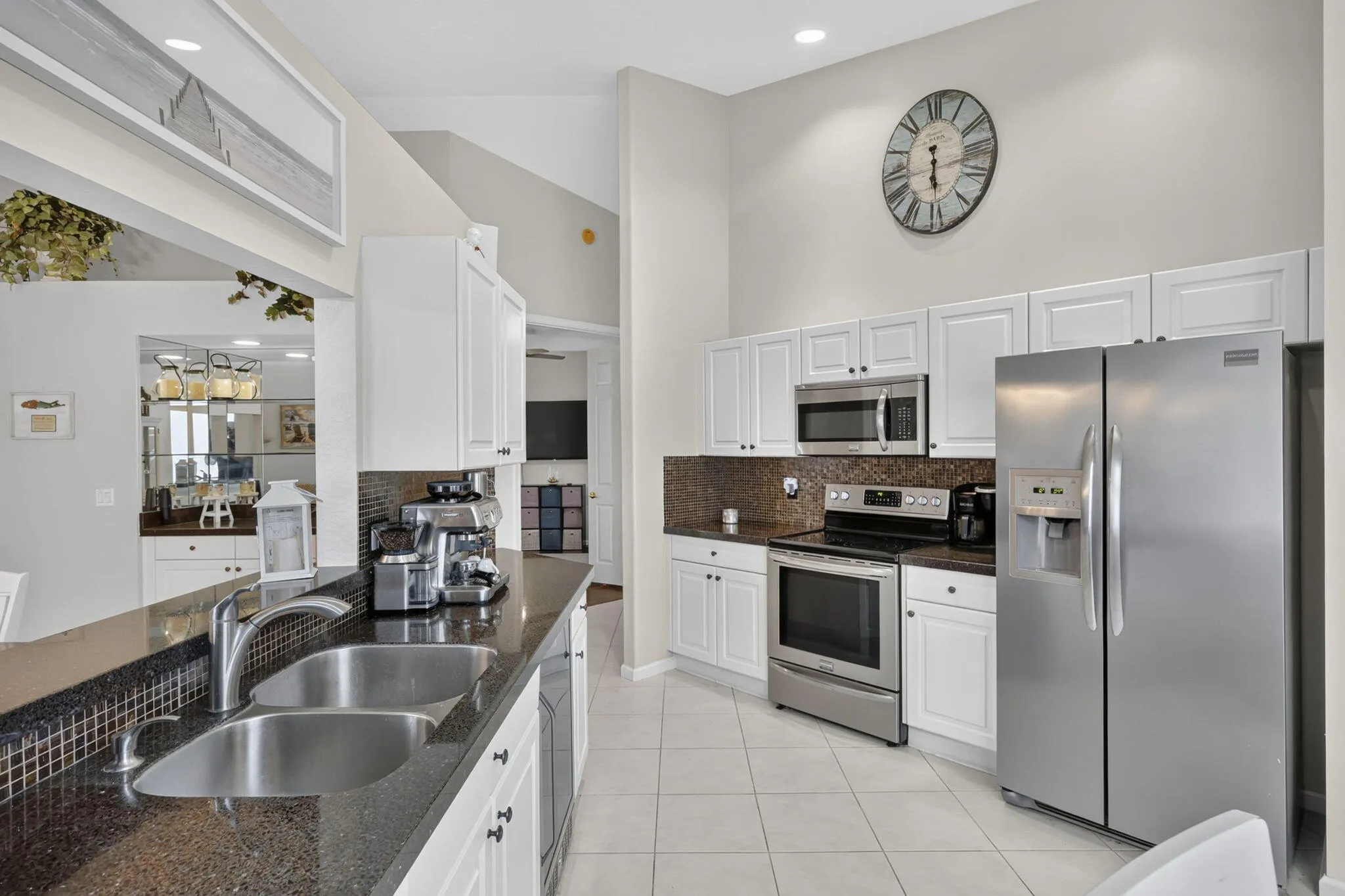 Kitchen featuring stainless steel appliances, white cabinetry, dark countertops, and a dual basin sink