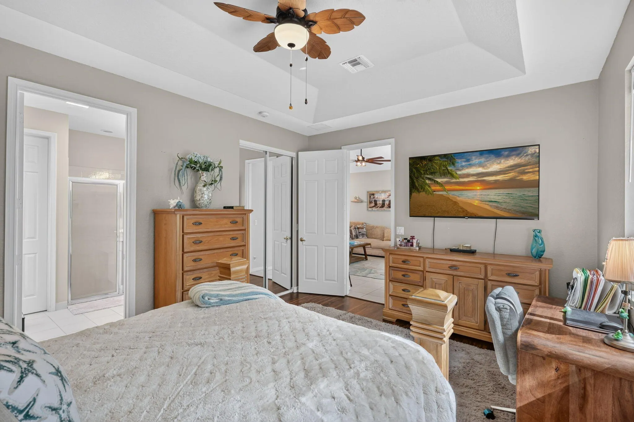 Recessed tray ceiling with a ceiling fan, light gray wall paint, and white trim