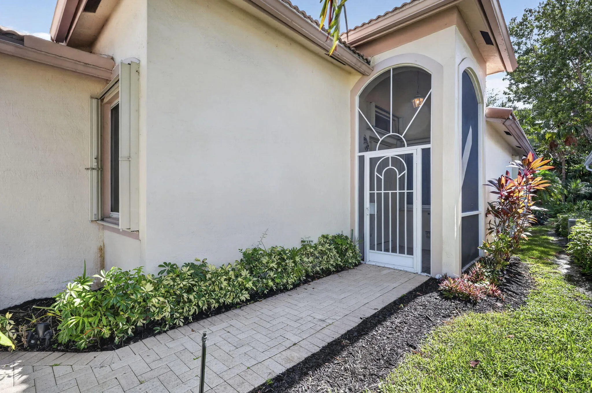 Stucco exterior with a tiled roof and hurricane shutters