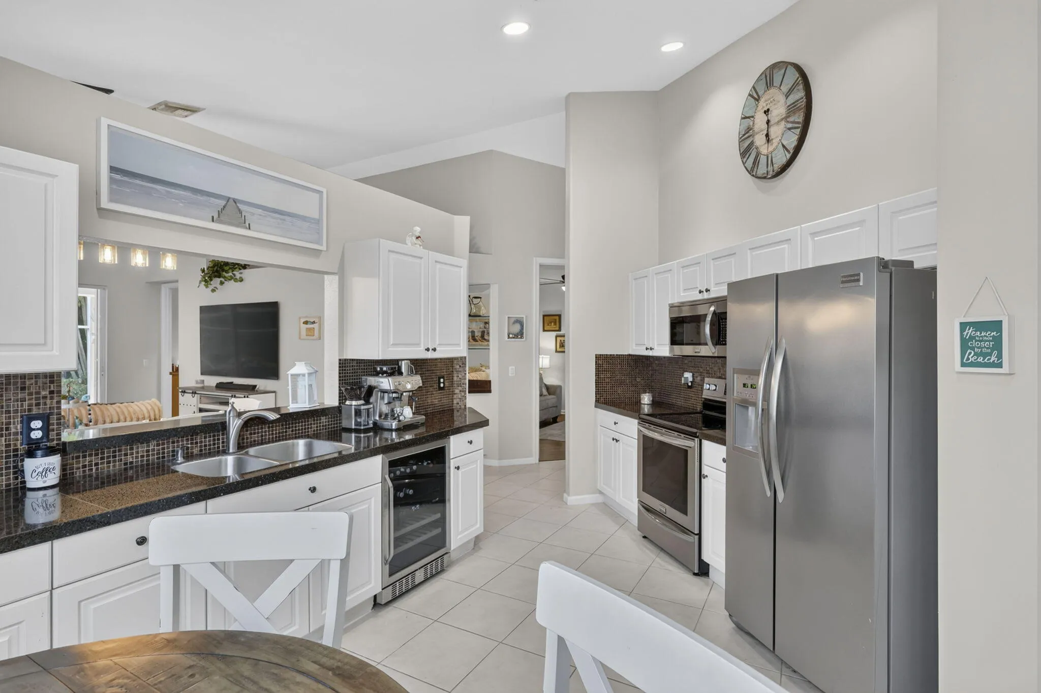 Kitchen featuring white cabinetry, dark countertops, a mosaic tile backsplash, stainless steel appliances, and tile flooring