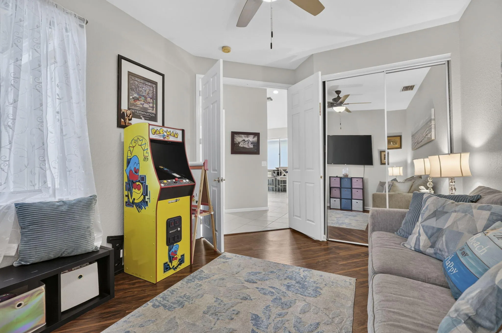 Wood-finish flooring with a ceiling fan, white paneled doors, and mirrored closet doors