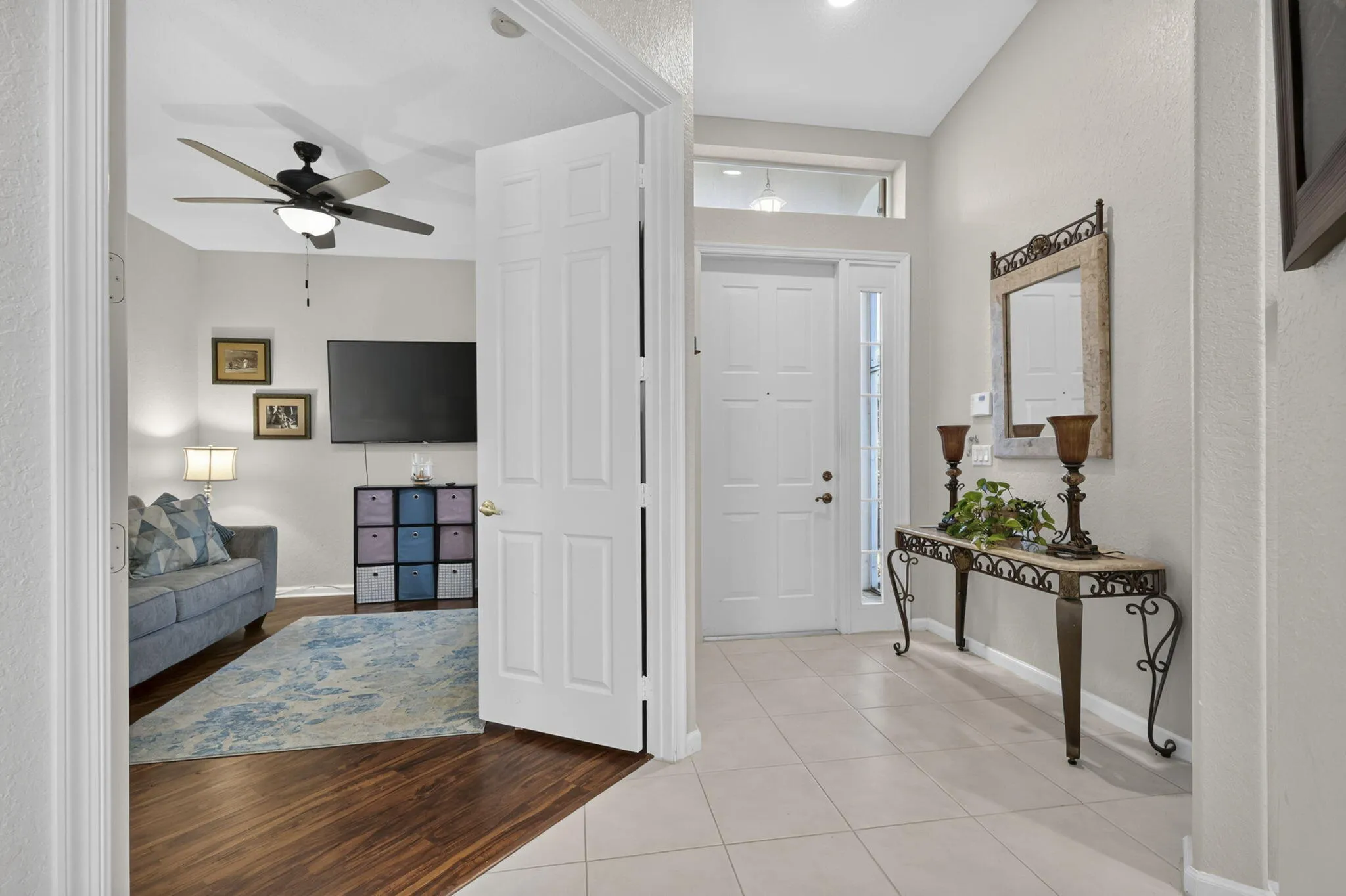 Entryway featuring a paneled door with sidelight and transom window, light-toned tile flooring, and a decorative console table