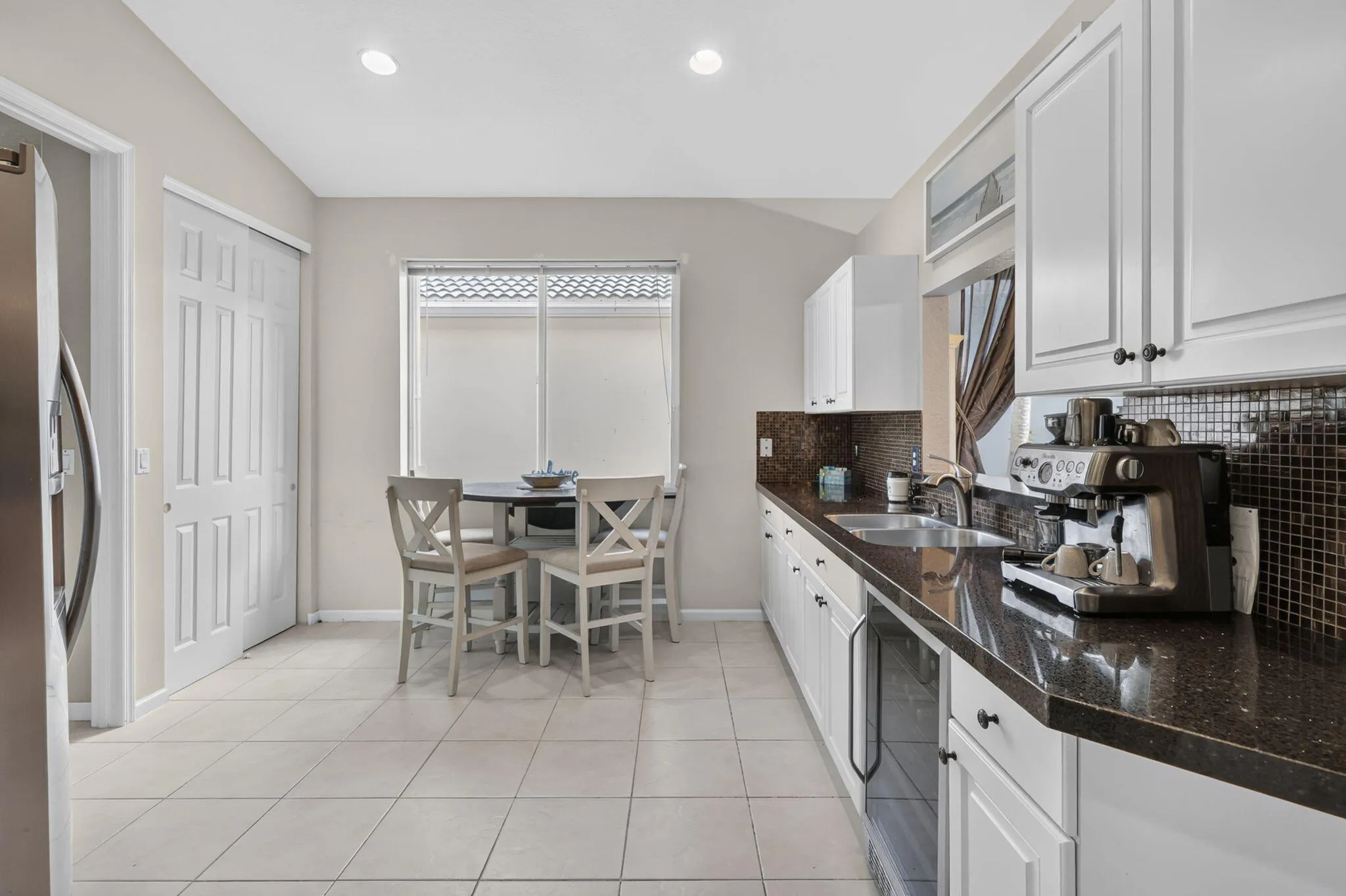 Kitchen featuring white cabinetry, dark countertops, a tile backsplash, and recessed lighting