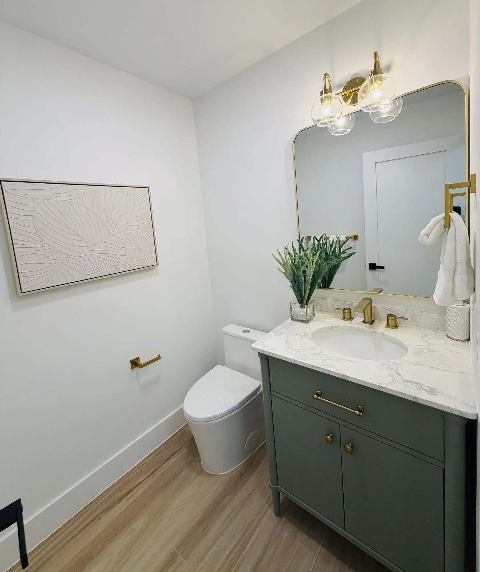 Modern vanity with a natural stone countertop, undermount sink, and brass-finish fixtures